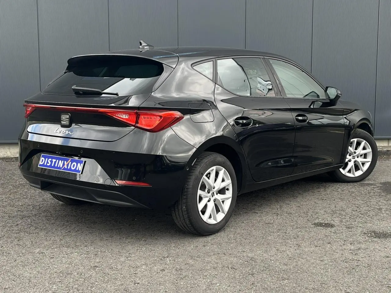 Vue 3/4 arrière droite d'une SEAT Leon 2024 noire Minuit avec vitres arrière surteintées et jantes alliage 16 pouces.