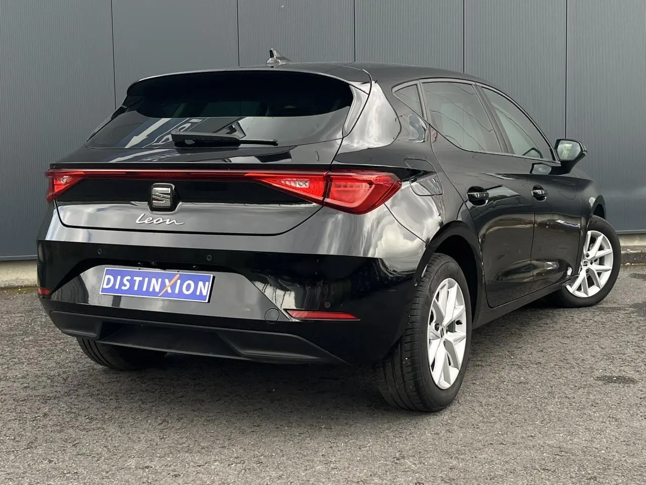 Vue 3/4 arrière droite d'une SEAT Leon 2024 noire Minuit avec feux arrière LED et jantes alliage 16 pouces.