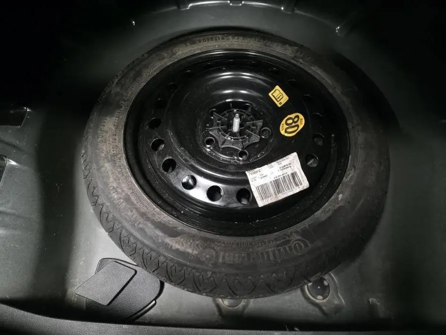 Gros plan sur la roue de secours noire 16 pouces du coffre de l'Opel Insignia 2016 avec étiquettes visibles.