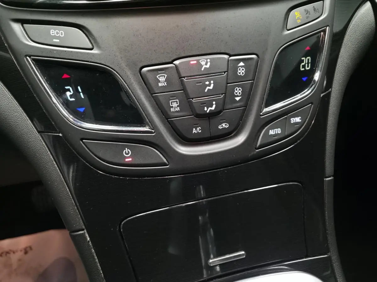 Vue rapprochée de la console centrale noire de l'Opel Insignia 2016 avec commandes climatisation bi-zone et bouton eco.