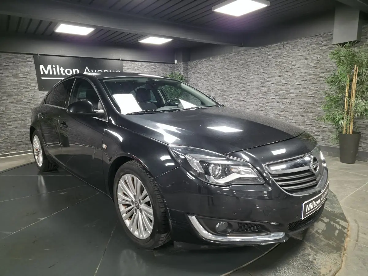 Opel Insignia noire vue en 3/4 avant droit, avec jantes alliage et calandre chromée dans un showroom.