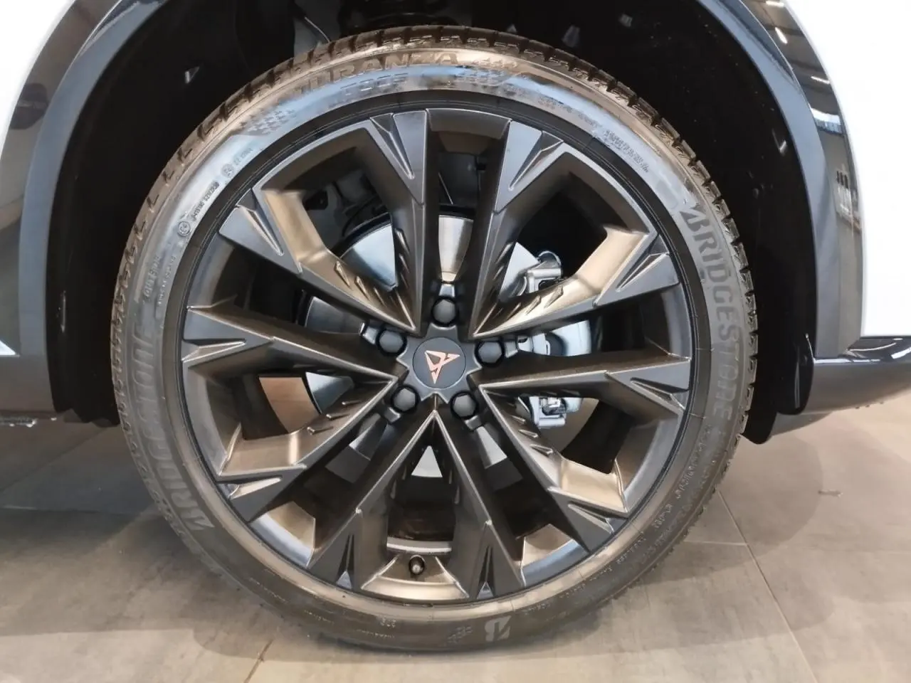 Gros plan sur la jante alliage 19'' Sandstorm noire du CUPRA Formentor Nevada White, avec logo Cupra central cuivré.