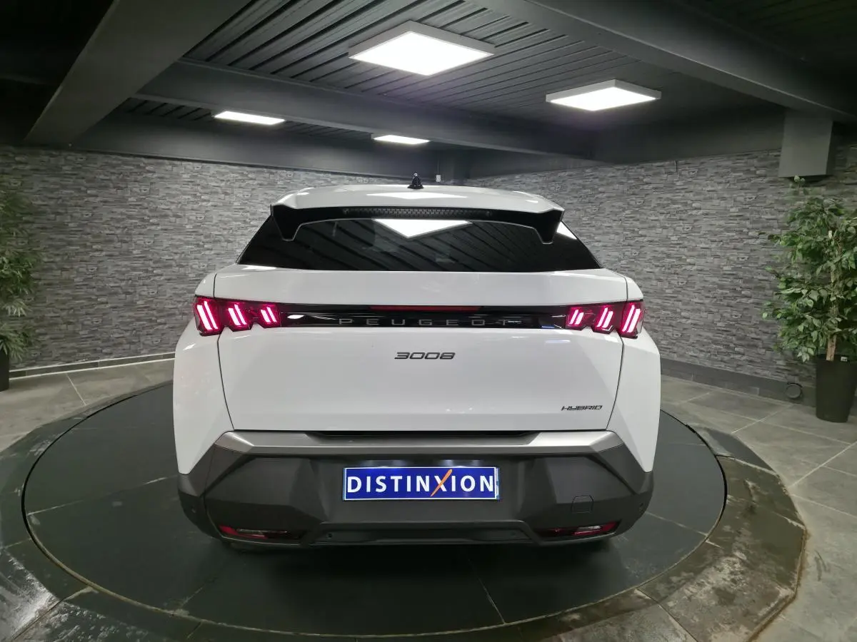 Vue arrière d'un Peugeot 3008 blanc hybride 2025 avec feux arrière LED à trois griffes et bandeau noir laqué.