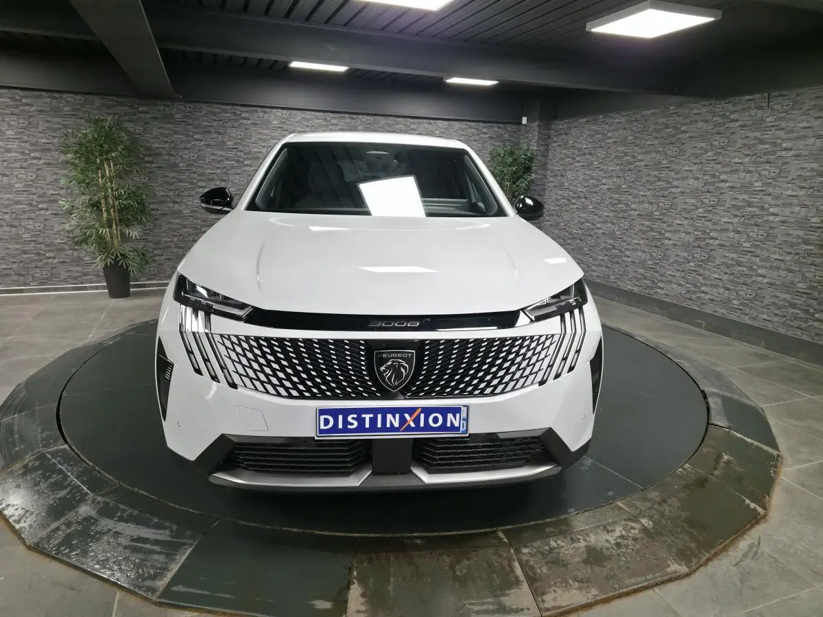 Peugeot 3008 blanc vue de face en intérieur, avec calandre noire à motif géométrique et logo lion central.