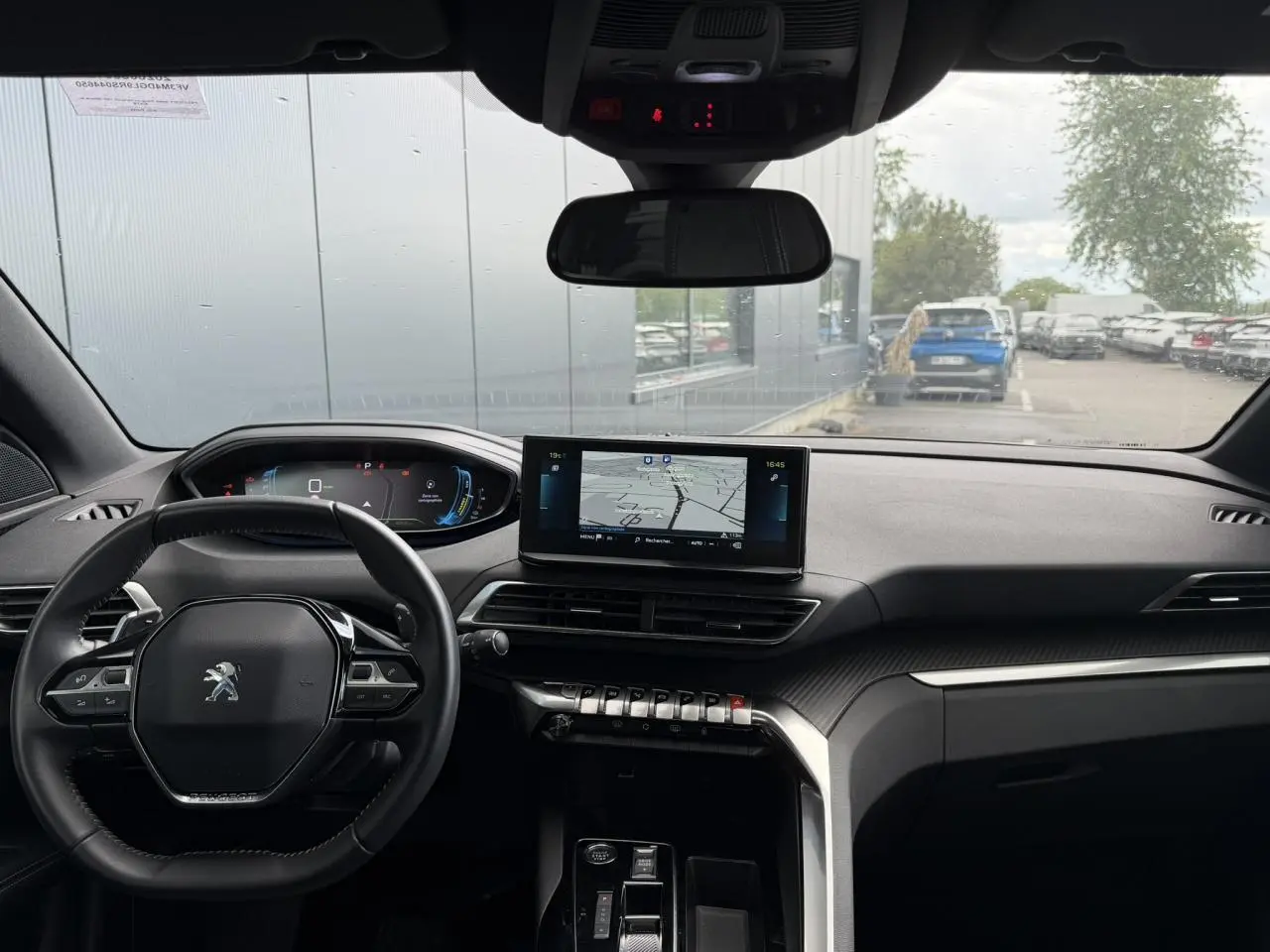 Vue intérieure avant du Peugeot 3008 Plug-in Hybrid 2024, tableau de bord noir avec écran tactile central et volant compact cuir.