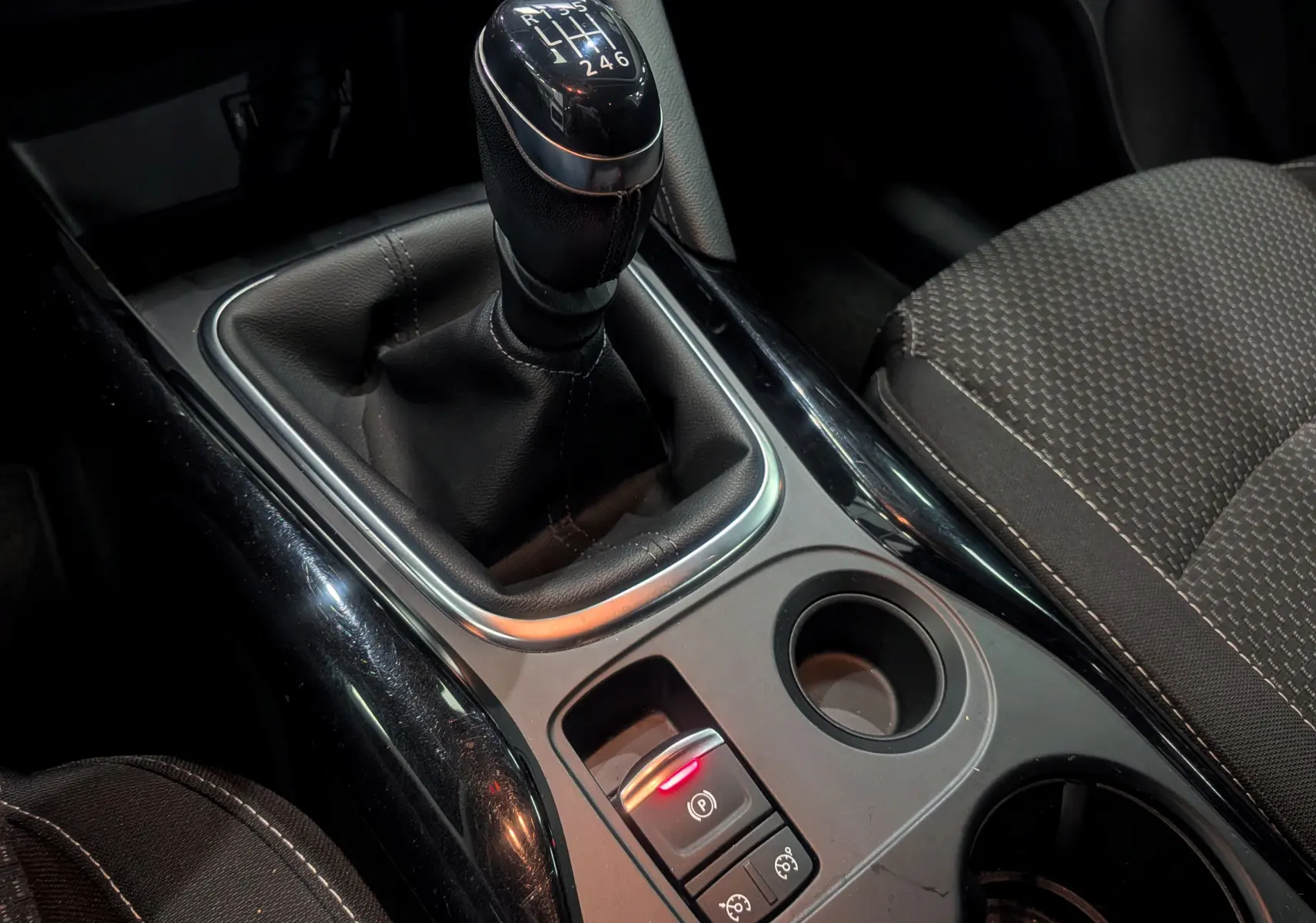 Gros plan sur la console centrale noire du Renault Kadjar 2020, avec levier de vitesse manuel et bouton frein à main électrique.