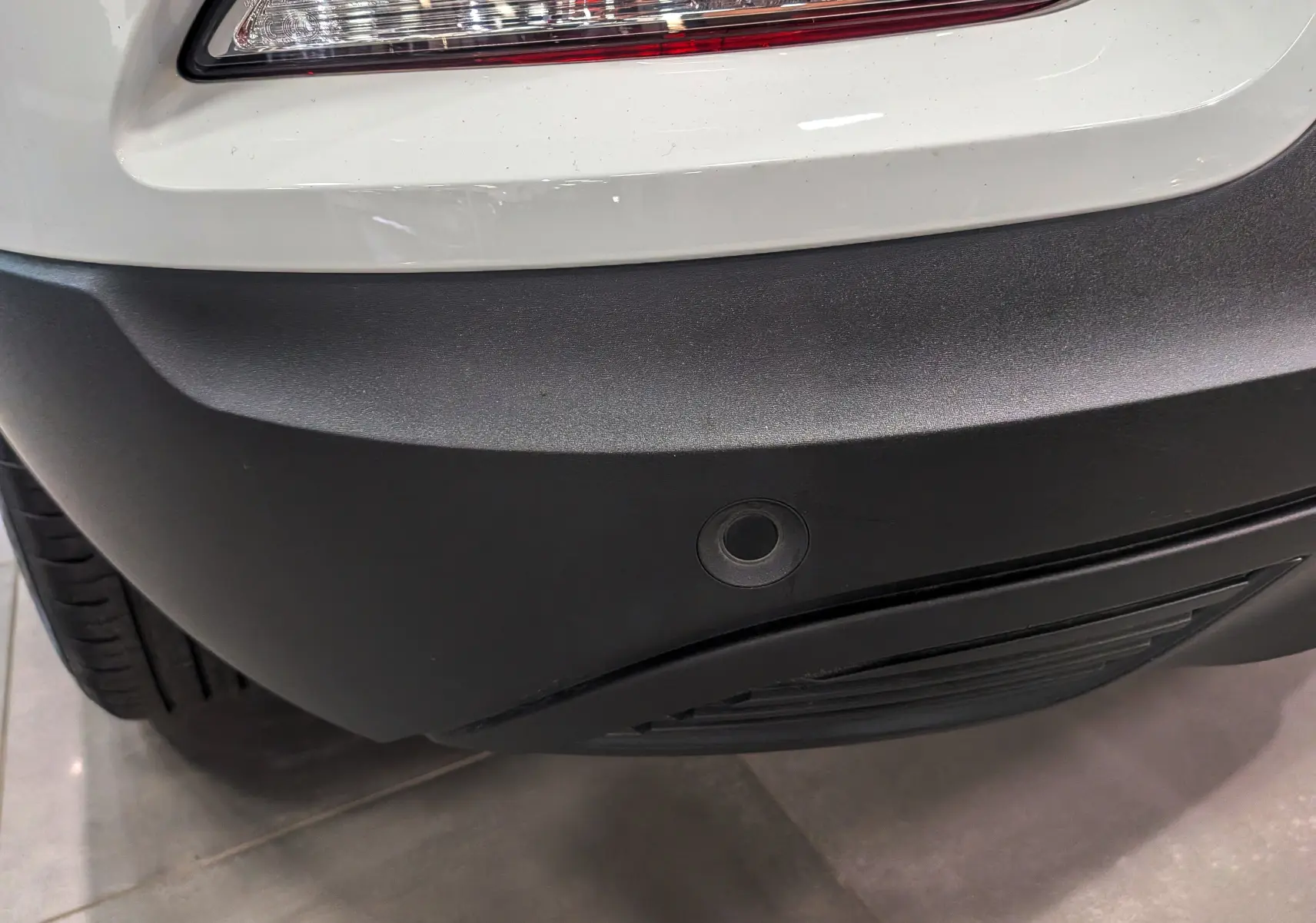 Gros plan sur le pare-chocs arrière noir et blanc glacier du Renault Kadjar 1.5 Blue dCi 115 CH BUSINESS avec capteur de recul.