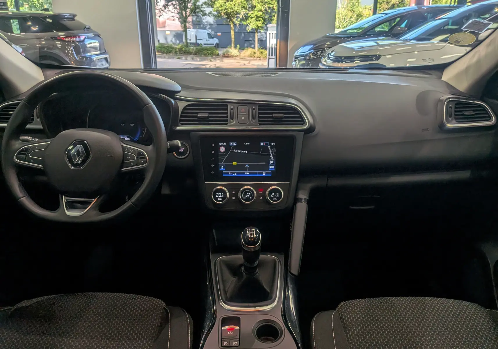Intérieur du Renault Kadjar 2020 en vue frontale, tableau de bord noir avec écran tactile et levier de vitesse manuel.