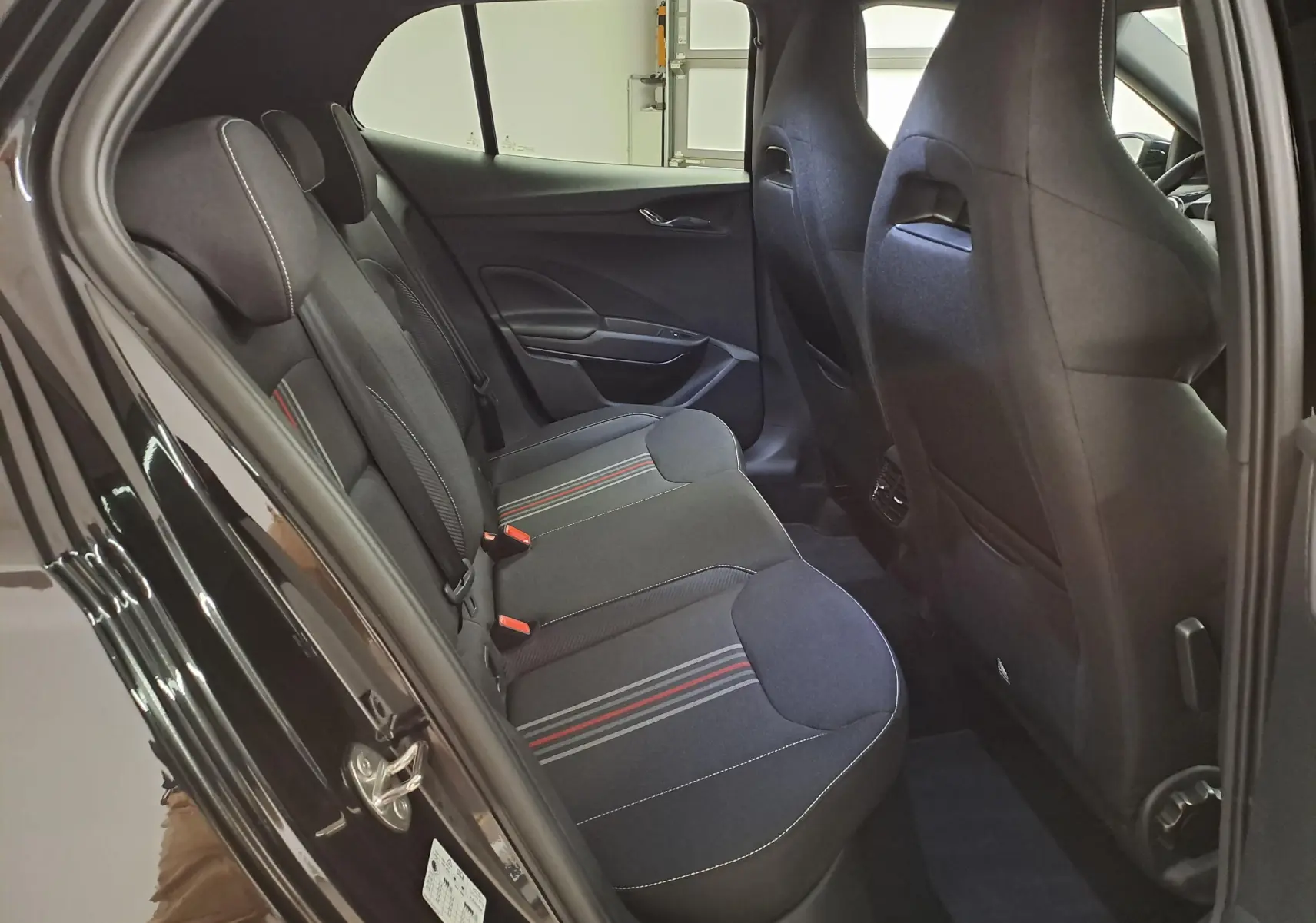 Vue intérieure côté gauche des sièges arrière noirs avec surpiqûres rouges et blanches dans une Skoda Fabia 2024.