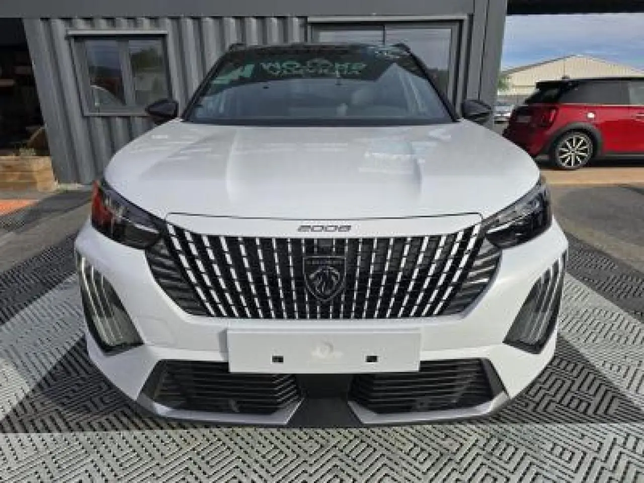 Vue frontale du Peugeot 2008 blanc Okenite avec calandre noire verticale et toit noir brillant.