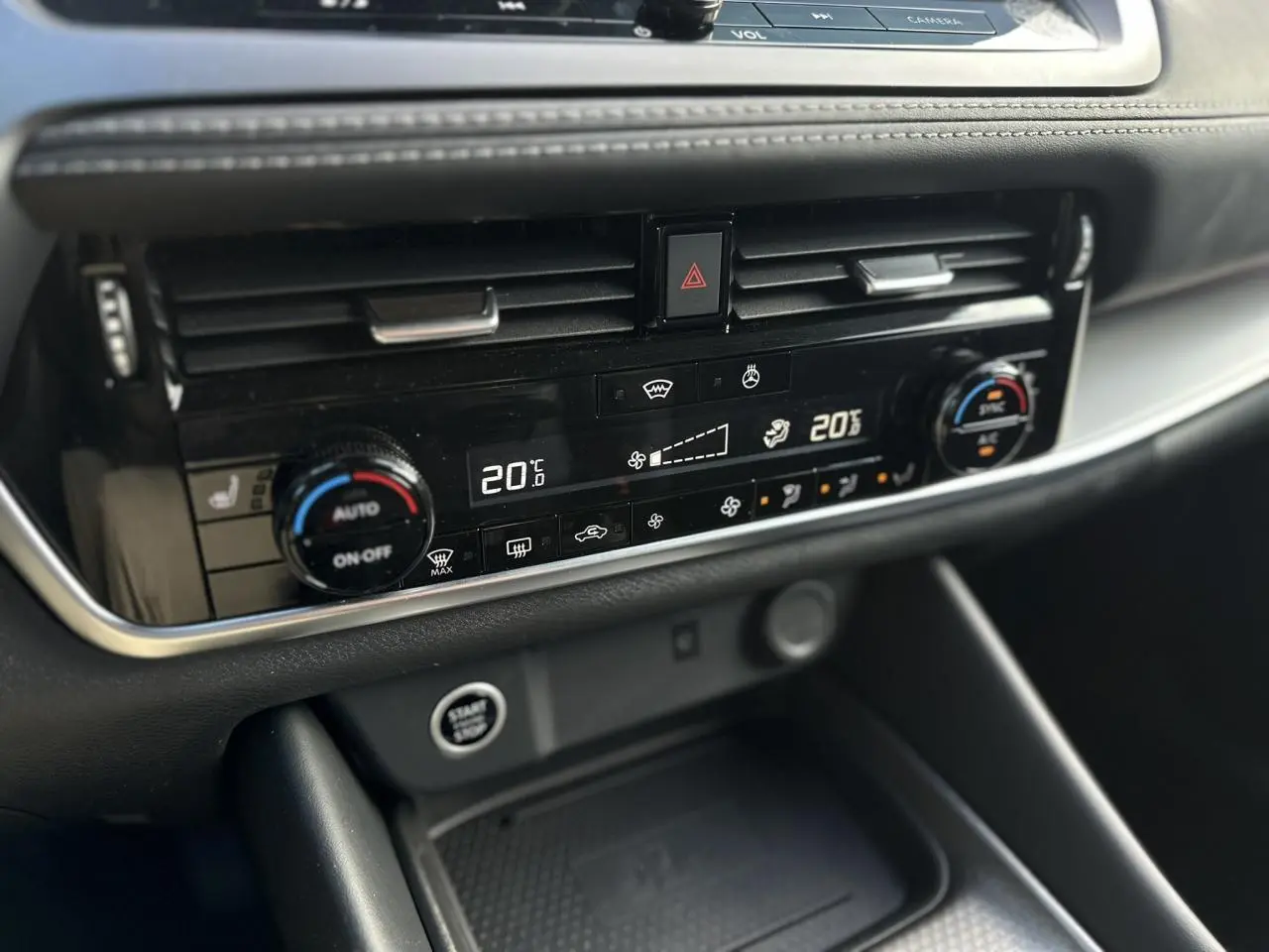 Vue rapprochée de la console centrale noire du Nissan Qashqai 2025, mettant en valeur la climatisation automatique bi-zone et le bouton Start/Stop.