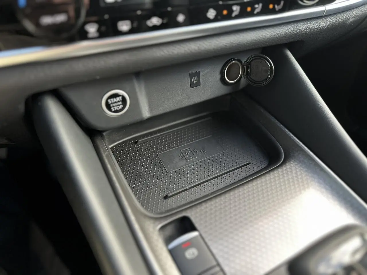 Gros plan sur la console centrale noire du Nissan Qashqai 2025 avec bouton start/stop et chargeur sans fil.