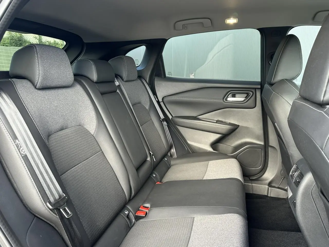 Vue intérieure côté droit des sièges arrière en tissu noir et gris du Nissan Qashqai 2025 avec ceinture à rayures.