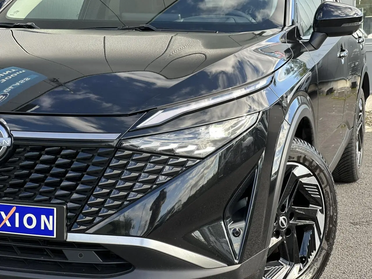 Vue 3/4 avant droit du Nissan Qashqai noir nacré mettant en valeur la calandre et les jantes alliage 18 pouces.