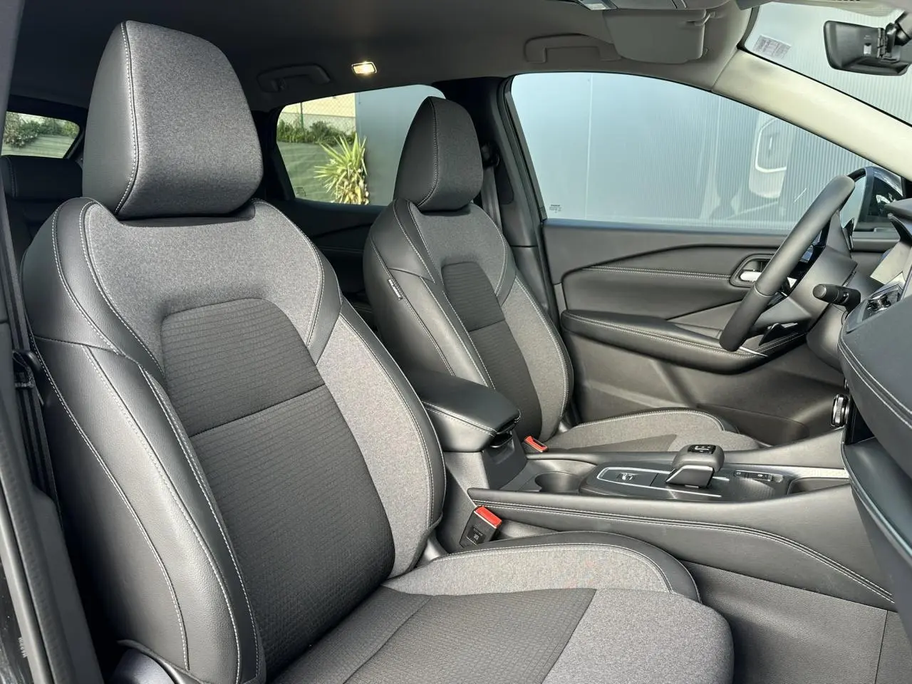 Intérieur du Nissan Qashqai 2025, vue côté droit sur sièges avant gris et noir avec console centrale moderne.
