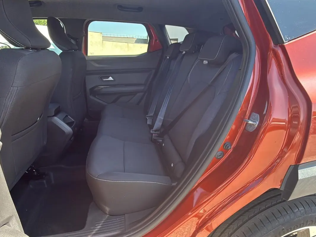 Vue intérieure des sièges arrière noirs du Dacia Duster orange 2025, porte arrière droite ouverte.