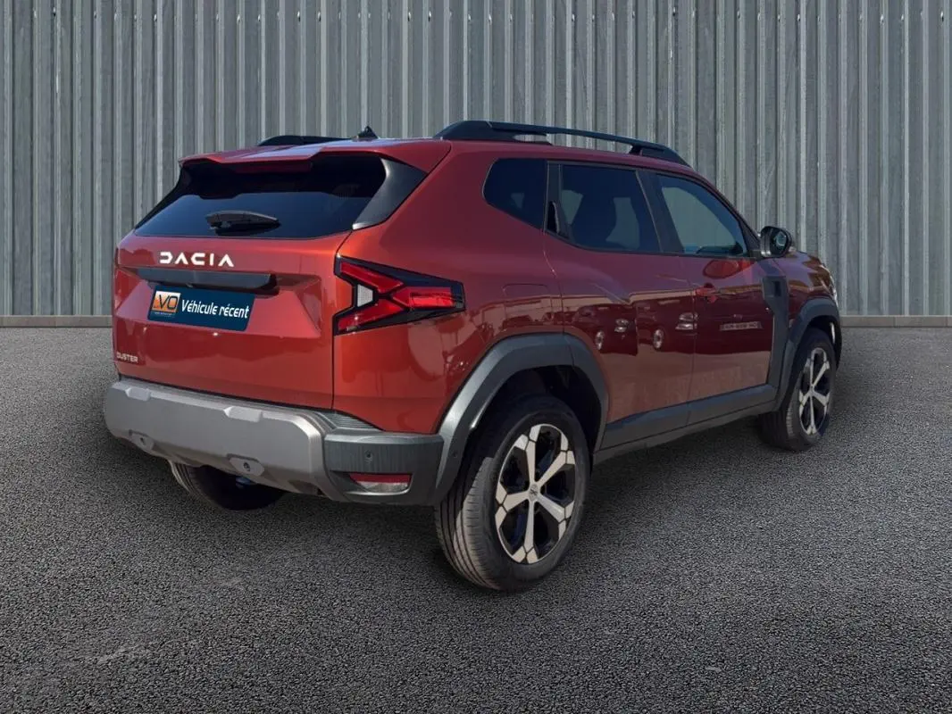 Vue 3/4 arrière droite du Dacia Duster orange 2025 avec barres de toit et jantes alliage 18 pouces.