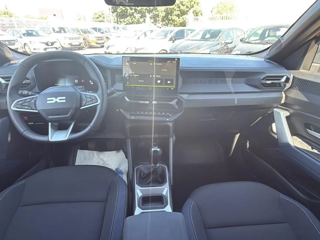 Vue intérieure avant du Dacia Duster 2025 avec tableau de bord moderne et écran tactile central.