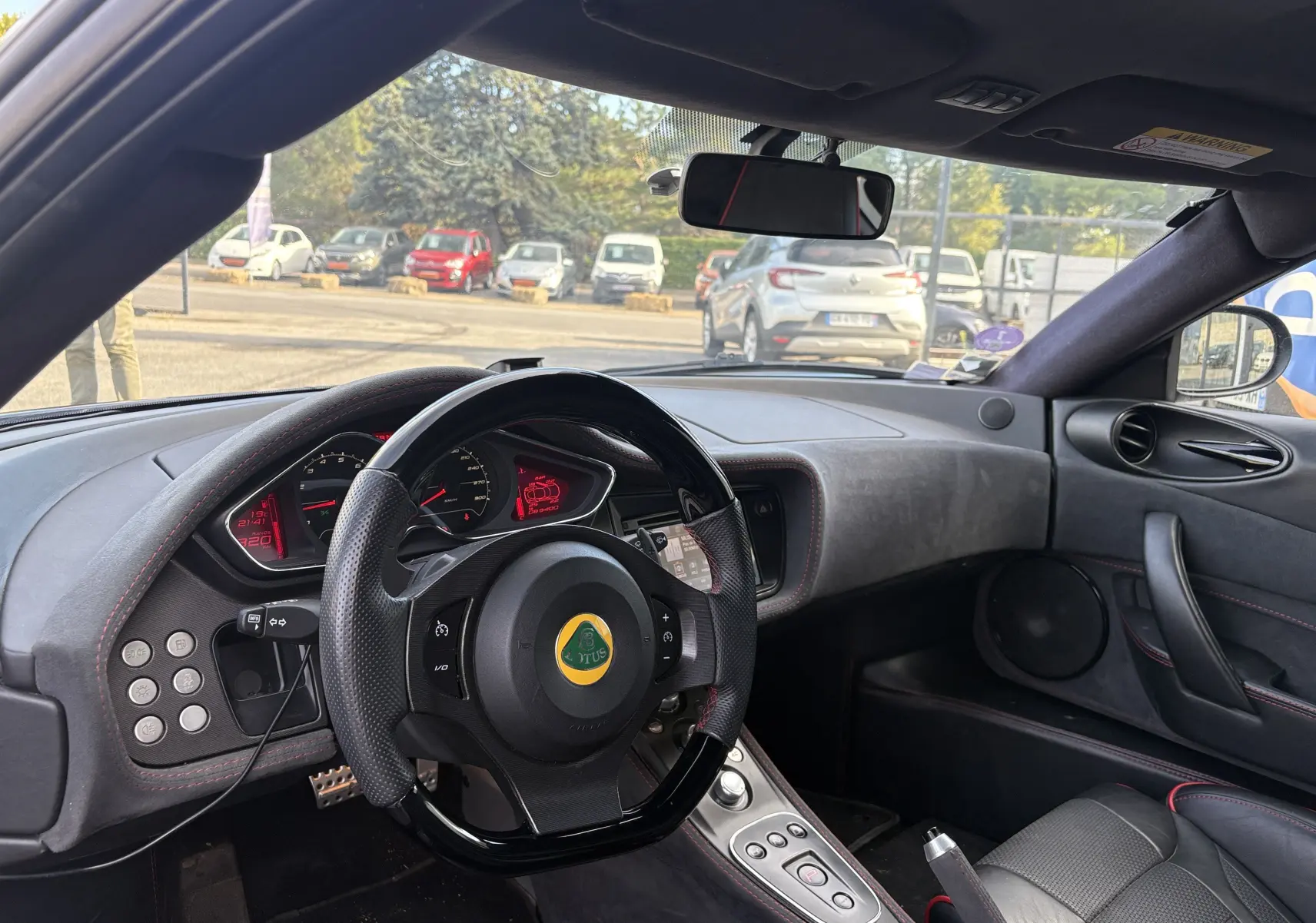 Intérieur du Lotus Evora 3.5 V6 S 2015 en Nightfall blue, vue du poste de conduite avec volant et tableau de bord visibles.