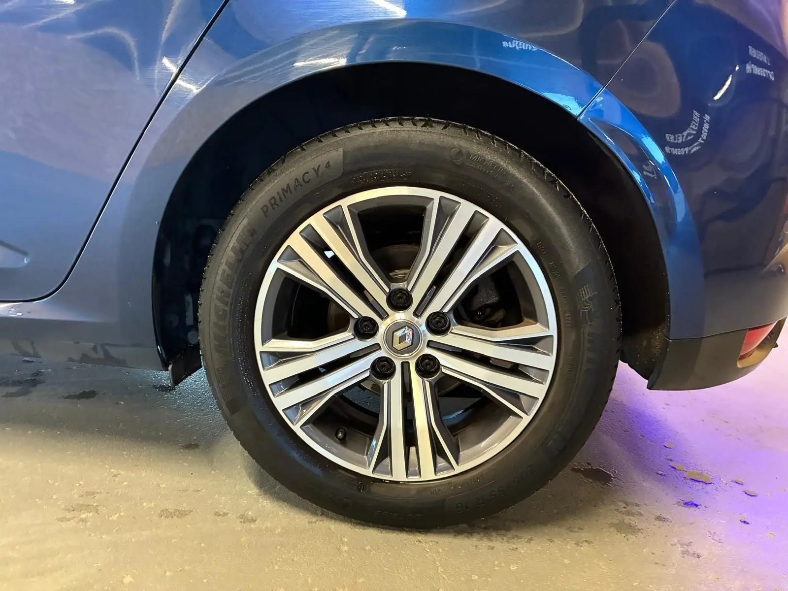 Gros plan sur la roue arrière droite d'une Renault Mégane bleu 2021, avec jante alliage bicolore et logo Renault central.