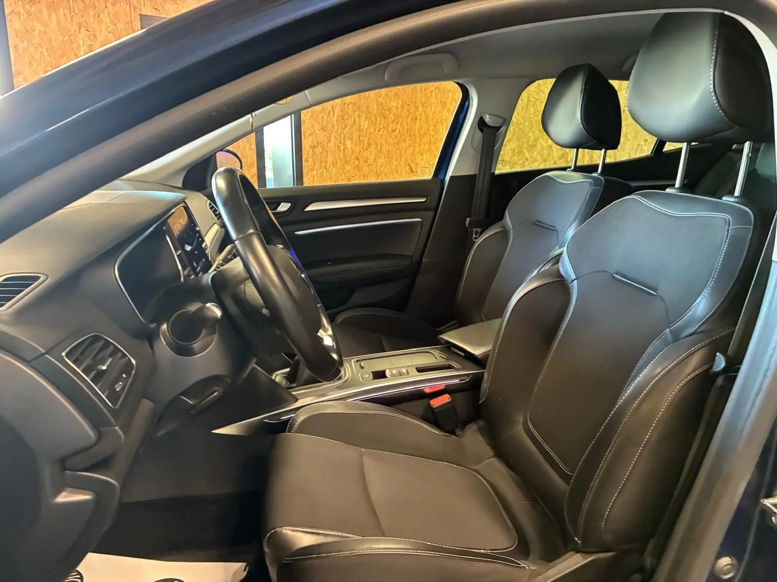 Intérieur avant droit d'une Renault Mégane 1.5 DCI 115 Intens 2021 avec sièges cuir noir et tableau de bord moderne.