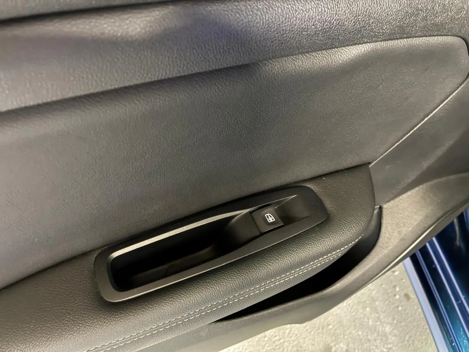 Gros plan sur la commande de lève-vitre côté gauche de la porte d'une Renault Mégane bleu 2021.