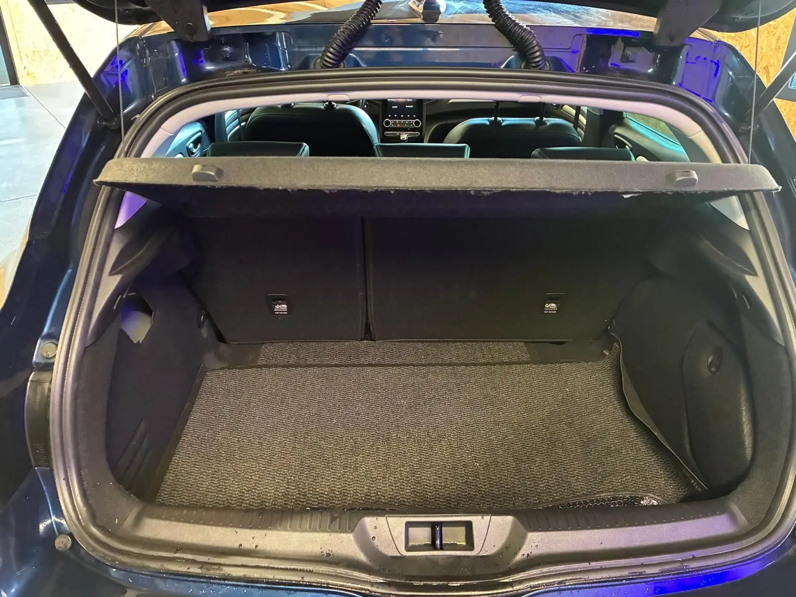 Coffre ouvert vu de l'arrière d'une Renault Mégane 1.5 dCi bleu, montrant l'espace de chargement et l'intérieur noir.
