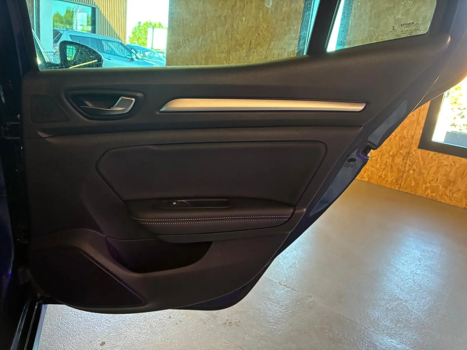 Vue intérieure de la porte arrière gauche d'une Renault Mégane 1.5 dCi 115 Intens bleue avec garniture noire et surpiqûres blanches.