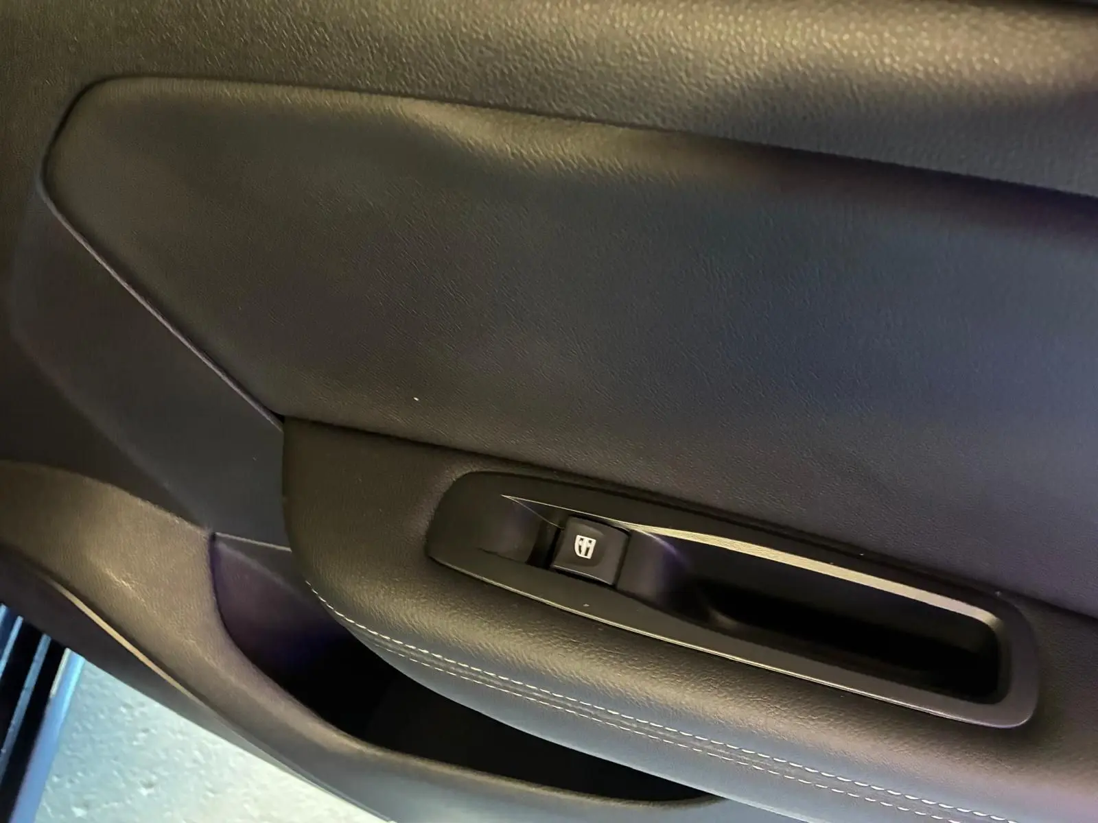 Détail de la commande de lève-vitre sur la porte intérieure côté conducteur d'une Renault Mégane bleu 2021.