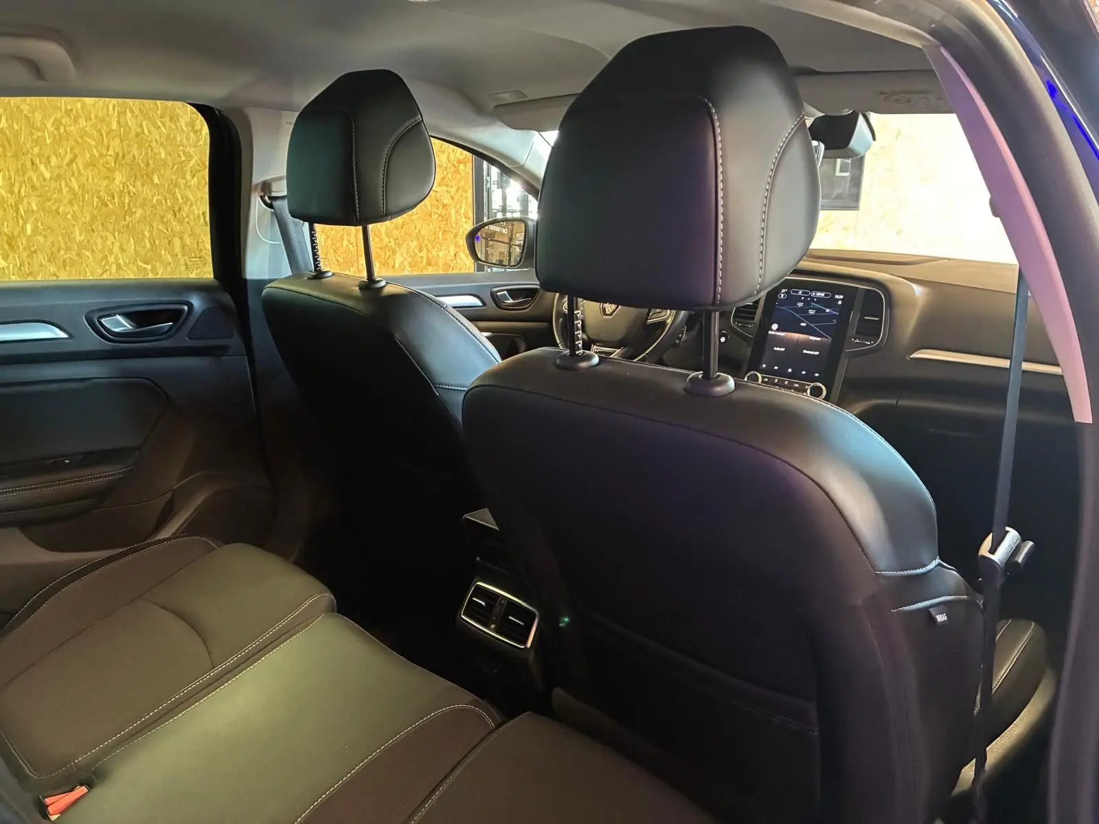 Vue intérieure arrière de la Renault Mégane 1.5 DCI 115 Intens 2021, sièges cuir noir et console centrale avec aérateurs.