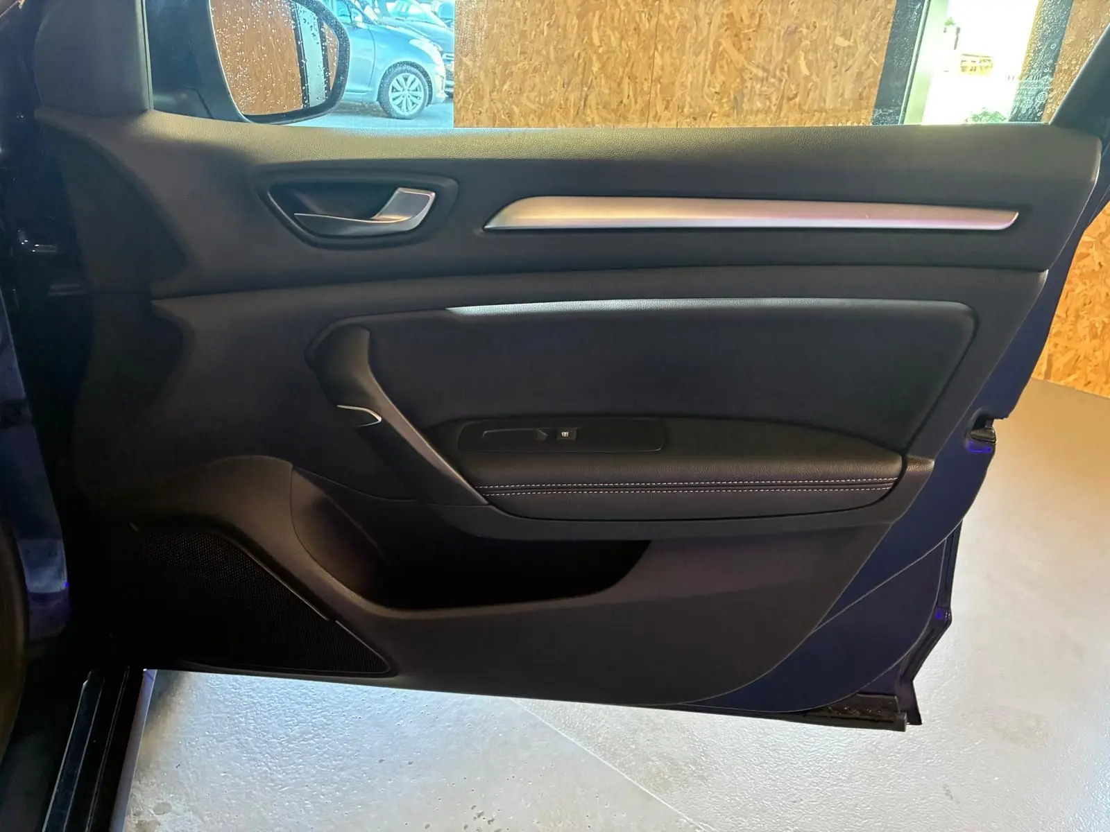 Vue intérieure de la porte avant gauche bleu Renault Mégane 1.5 DCI 115 Intens avec garniture noire et surpiqûres blanches.