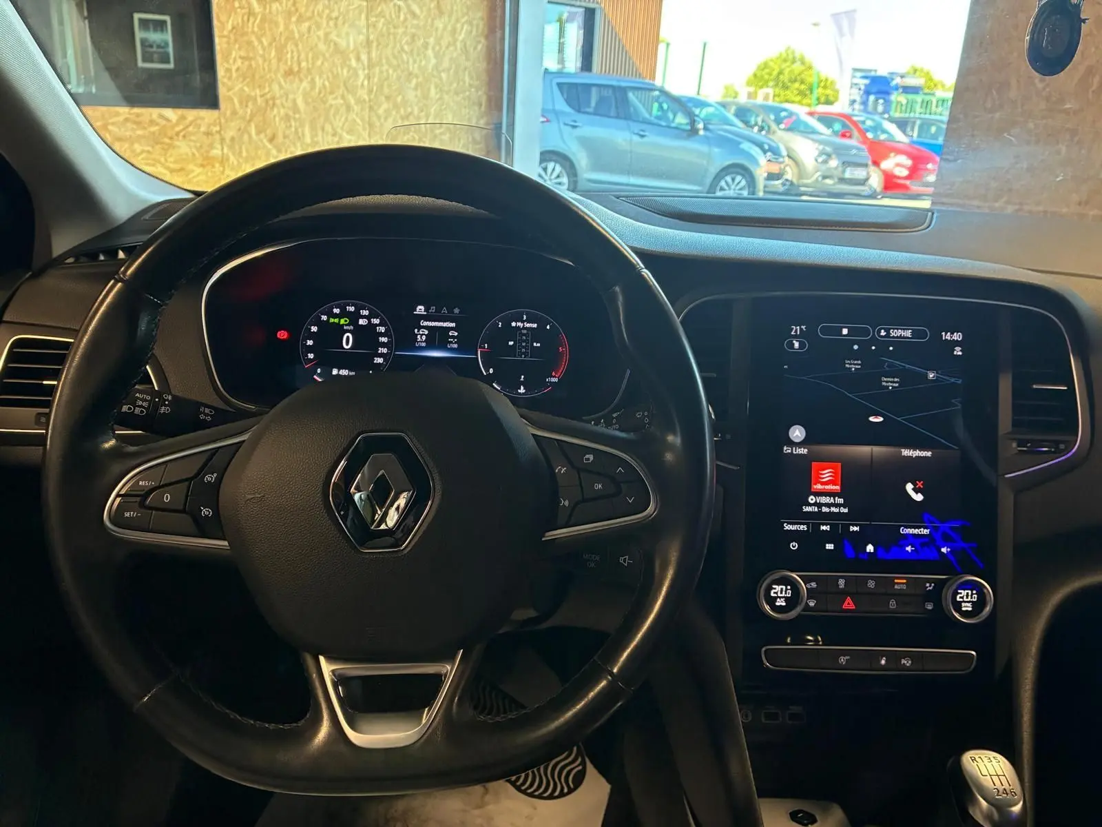 Vue intérieure centrée sur le volant noir Renault et l'écran tactile du tableau de bord de la Mégane bleue 2021.