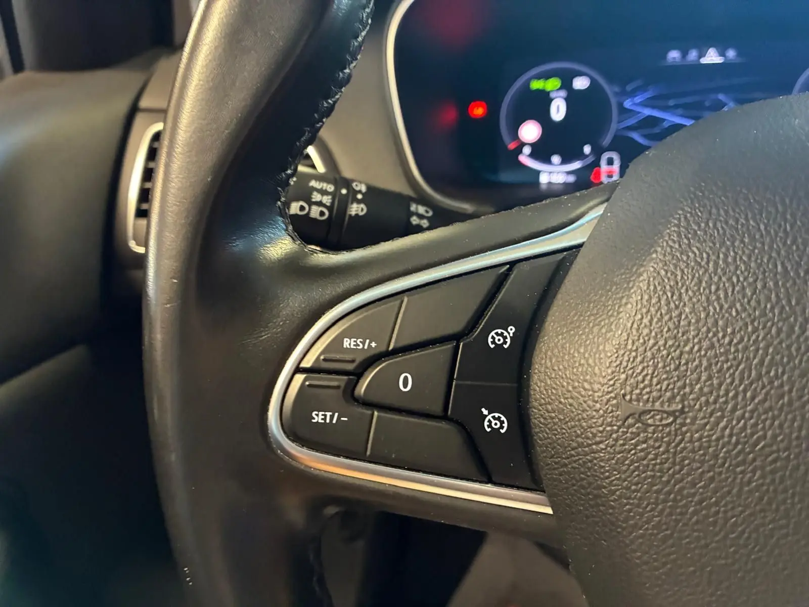 Gros plan sur les commandes de régulateur de vitesse au volant noir d'une Renault Mégane 1.5 DCI 115 Intens 2021.