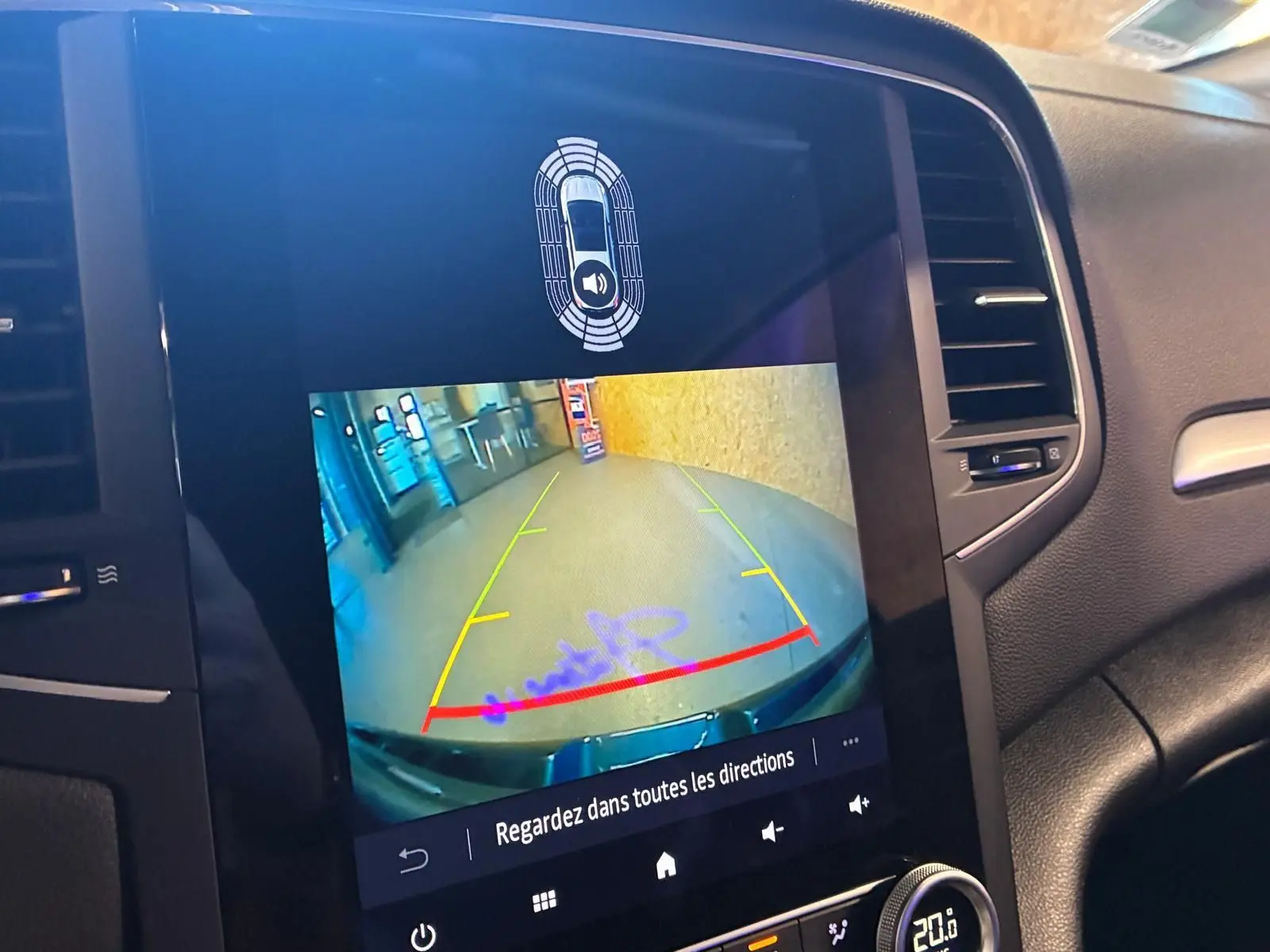 Vue rapprochée de l'écran multimédia d'une Renault Mégane bleu 2021 montrant la caméra de recul avec guidage coloré.