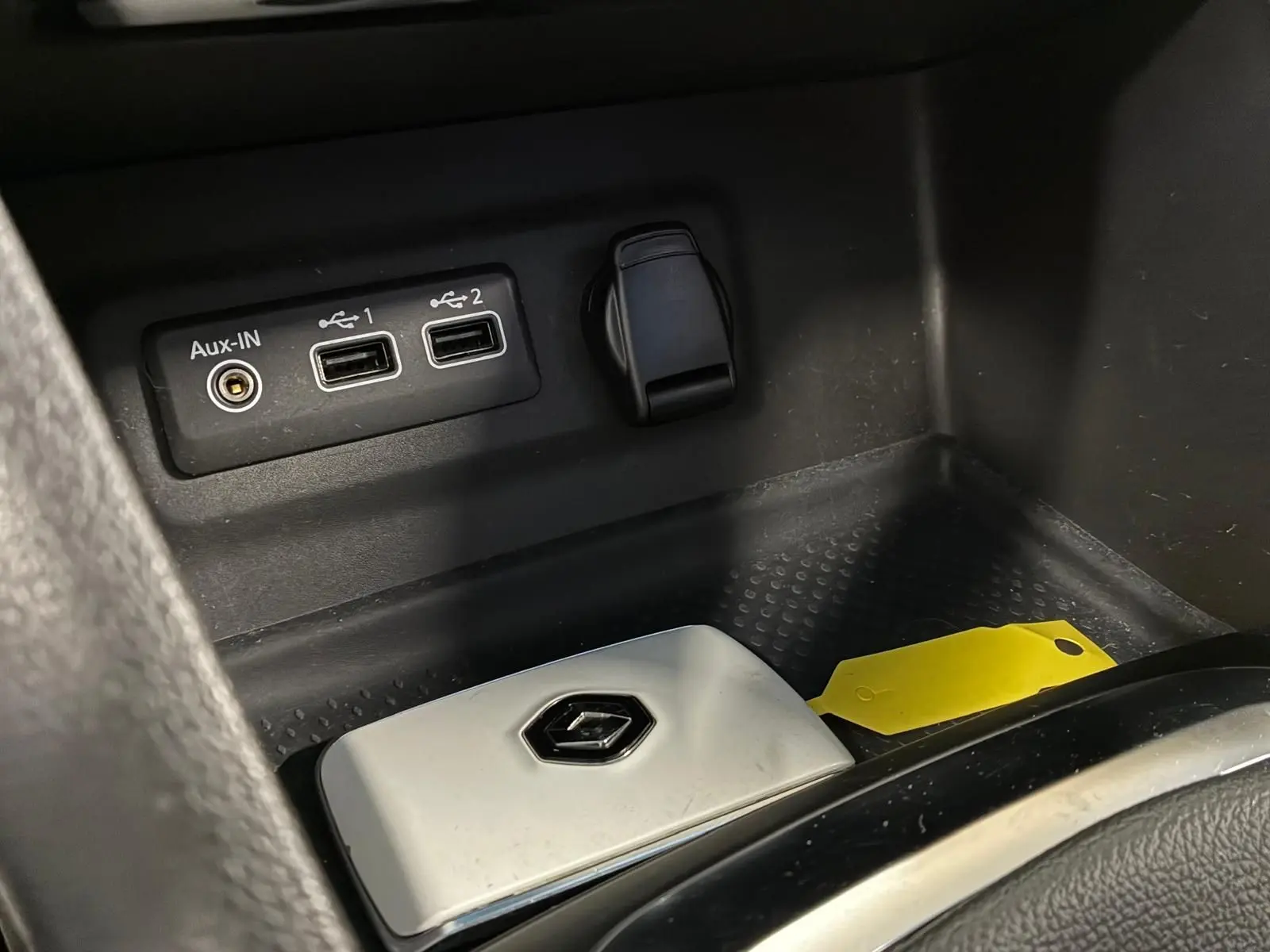 Gros plan sur la console centrale noire avec ports USB, prise auxiliaire et clé Renault blanche dans une Renault Mégane bleu 2021.