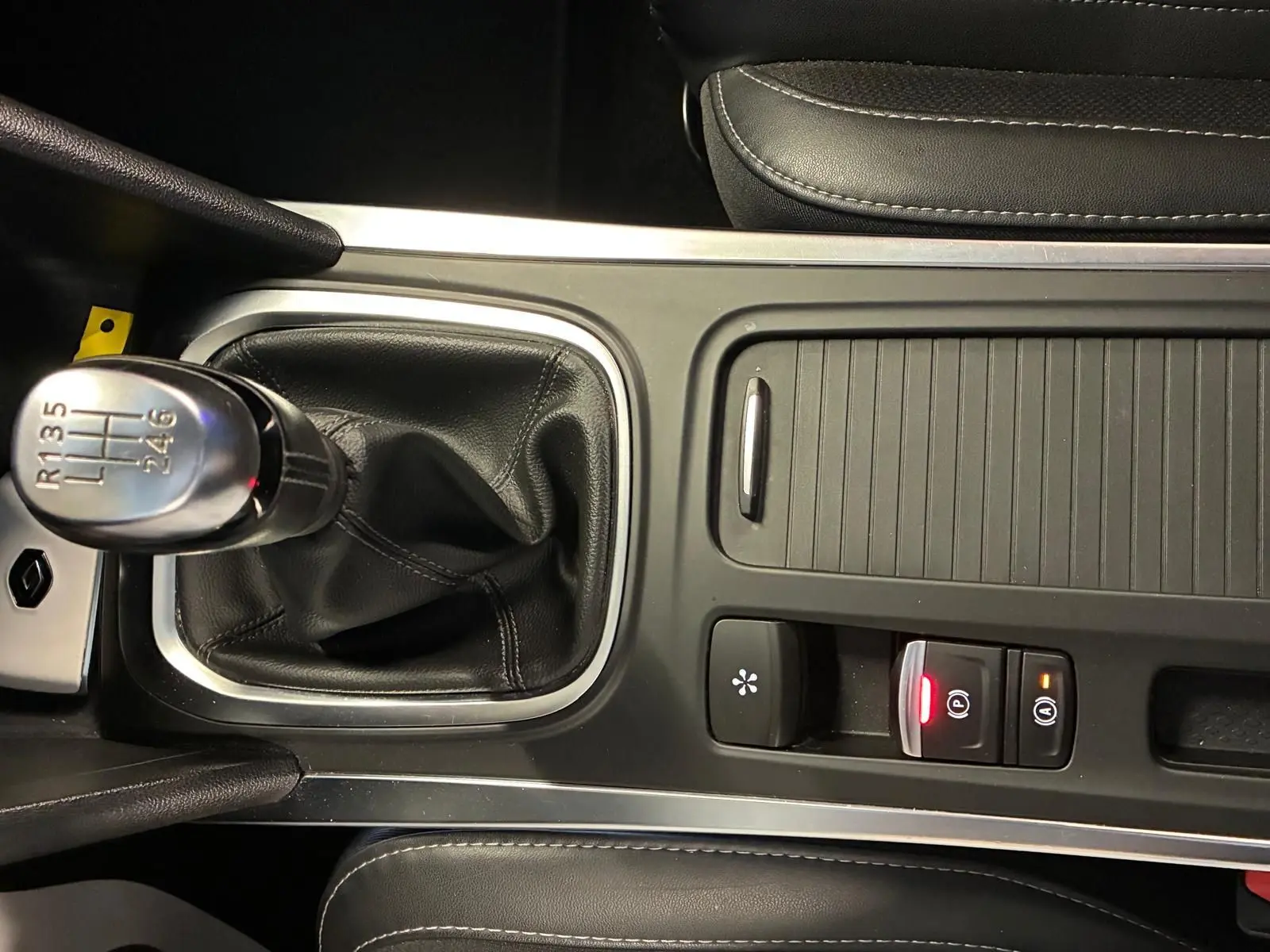 Gros plan sur la console centrale noire d'une Renault Mégane 1.5 DCI 115 Intens 2021 avec levier de vitesse manuel et commandes éclairées.