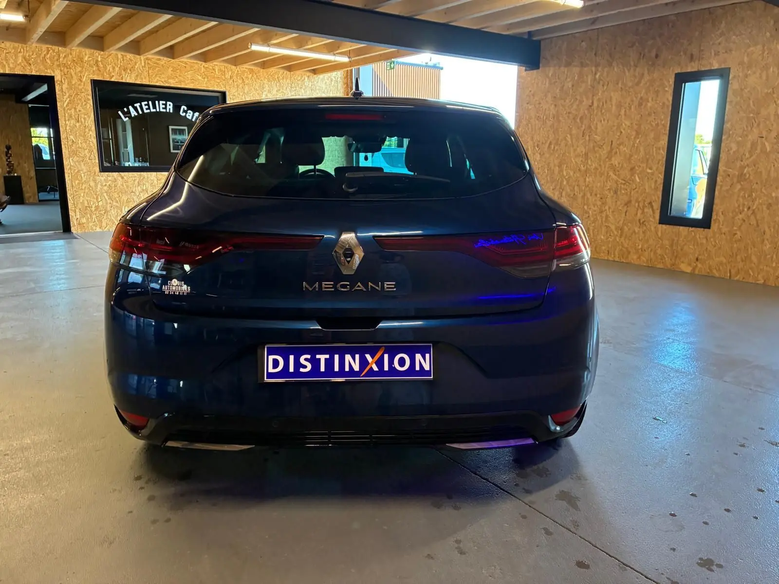 Vue arrière d'une Renault Mégane bleu foncé 2021 avec feux LED et logo Renault bien visibles dans un garage.