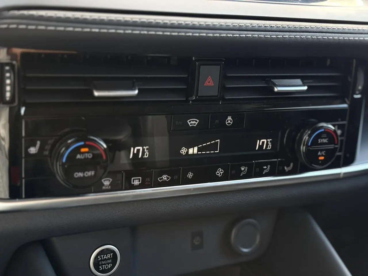 Panneau de climatisation automatique bi-zone noir avec commandes tactiles et bouton Start/Stop dans un Nissan Qashqai 2025.