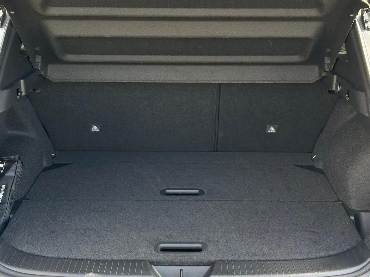 Coffre spacieux du Nissan Qashqai gris argent 2025 avec hayon électrique ouvert, plancher modulable et intérieur noir.