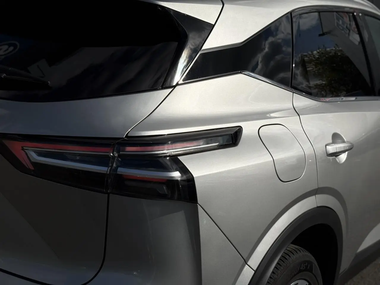 Vue arrière côté gauche du Nissan Qashqai gris argent 2025 avec feux arrière LED effilés et hayon électrique.