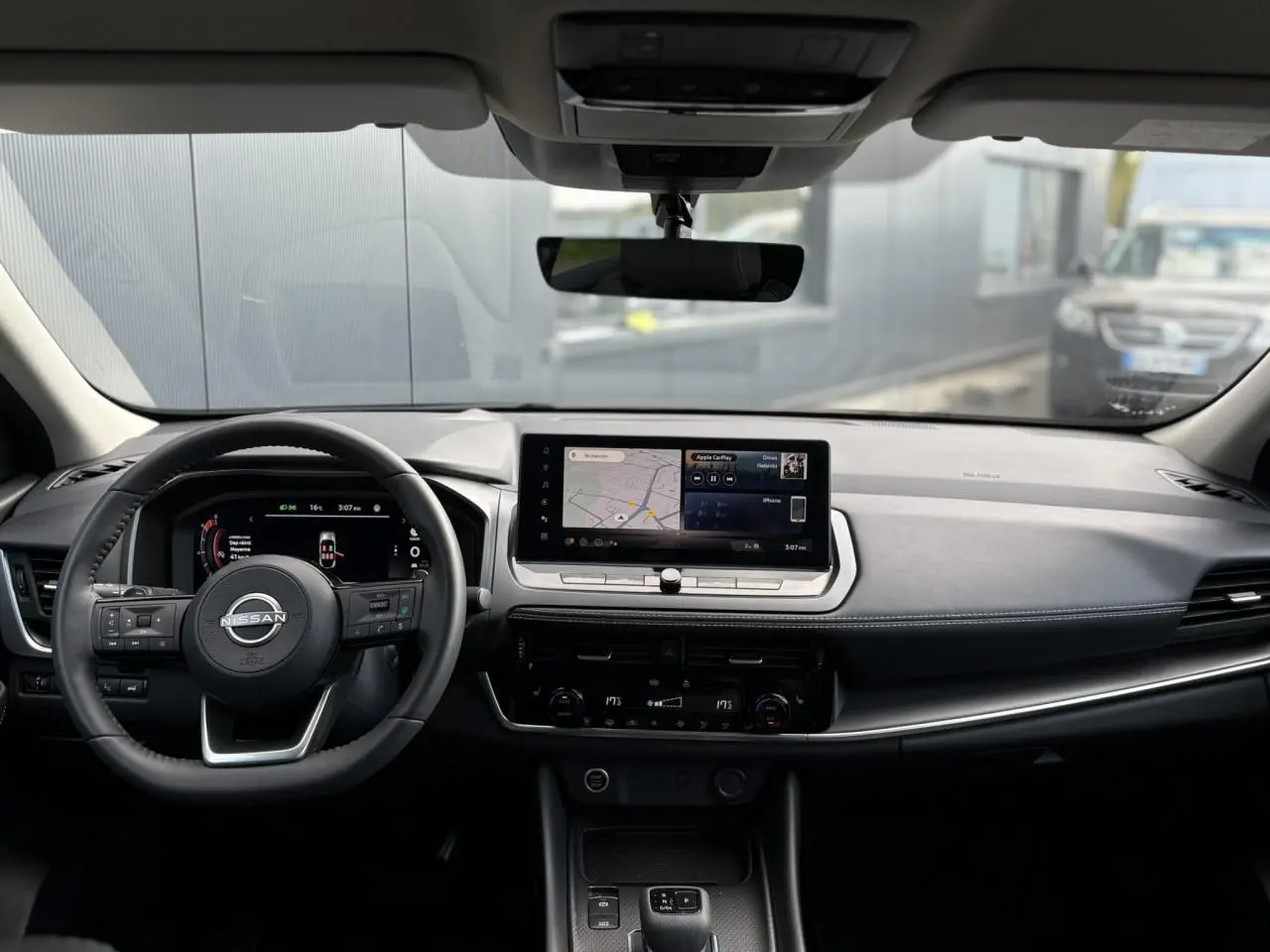 Intérieur du Nissan Qashqai 2025 vu de face, tableau de bord noir avec écran tactile et volant cuir multifonctions.