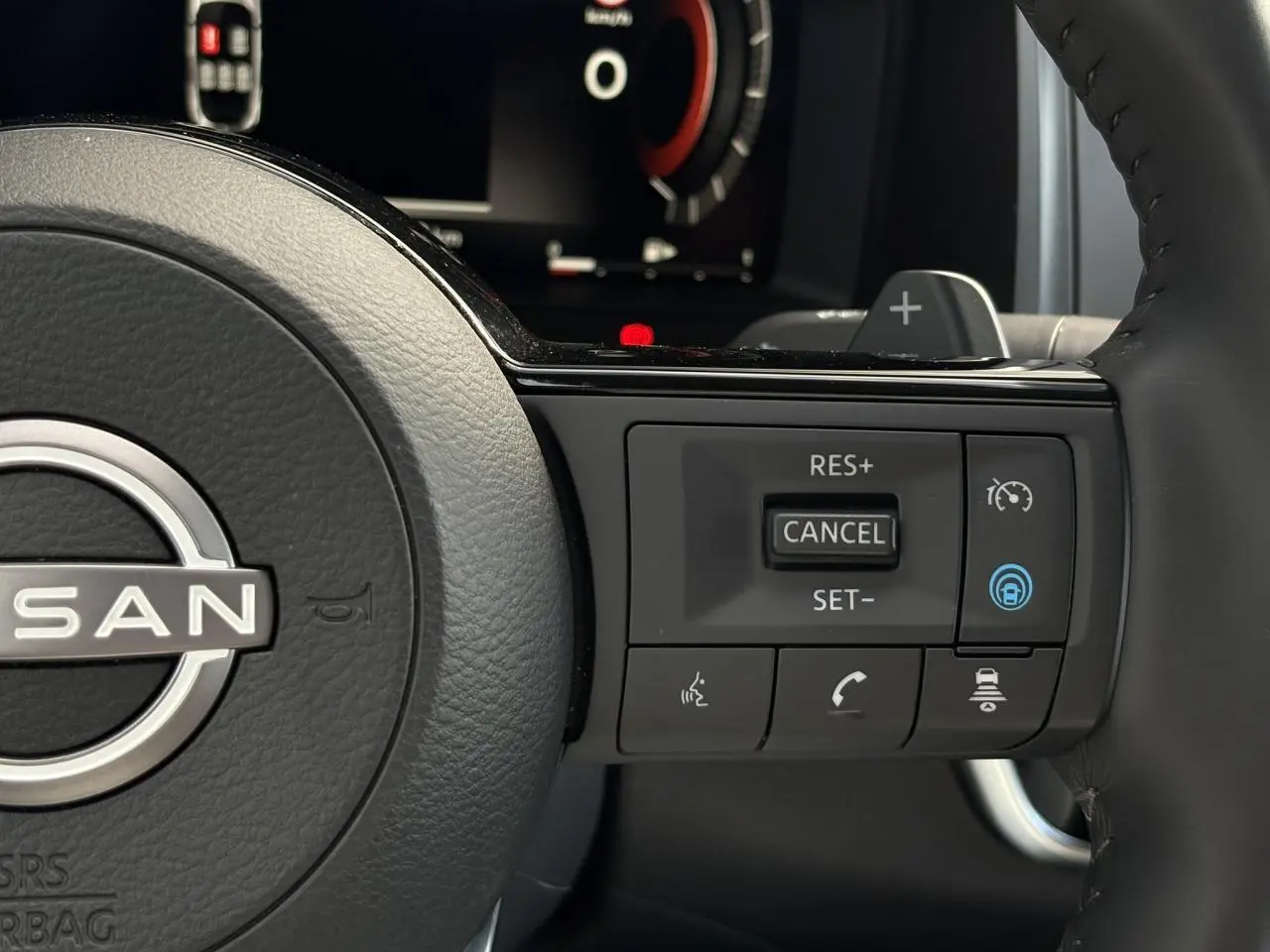 Gros plan sur le volant cuir noir du Nissan Qashqai 2025, avec commandes de régulateur et assistance active visibles