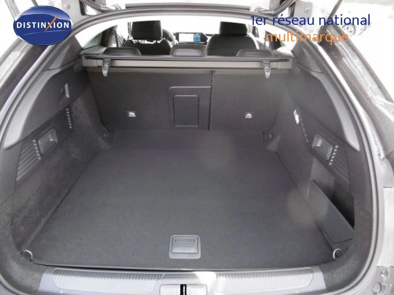 Coffre spacieux ouvert d'une Citroën C5 X gris platinium métal, vue arrière mettant en valeur l'intérieur noir et la tablette de séparation.