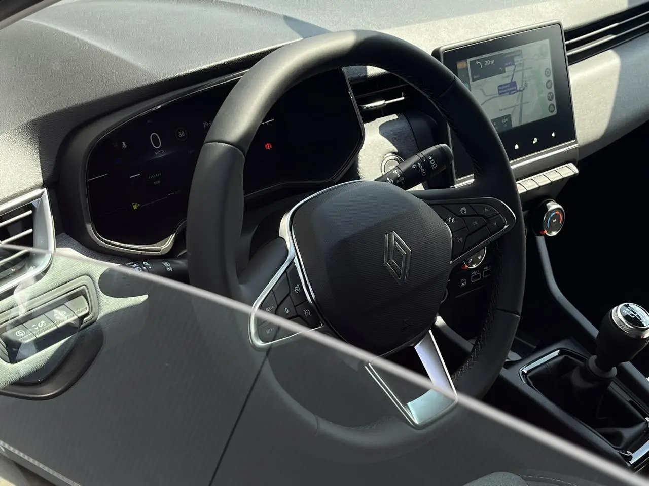 Vue intérieure rapprochée du volant multifonction et de la console centrale avec écran tactile de la Renault Clio blanche.