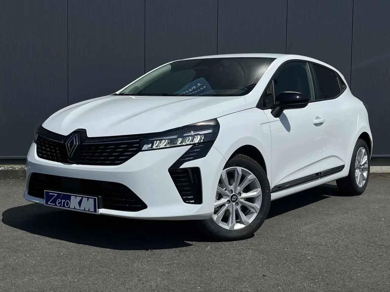 Renault Clio blanc glacier vue 3/4 avant droit avec jantes 16'' Boavista et rétroviseurs noirs.