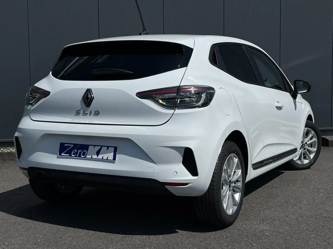 Renault Clio blanc glacier vue 3/4 arrière droit, vitres arrière surteintées et jantes 16'' Boavista visibles.