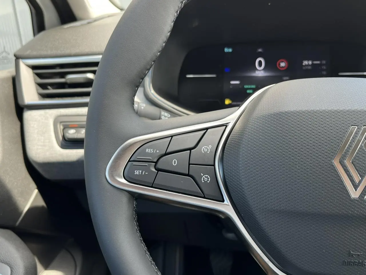 Gros plan sur le volant multifonction de la Renault Clio 2025, montrant les commandes de régulateur de vitesse.