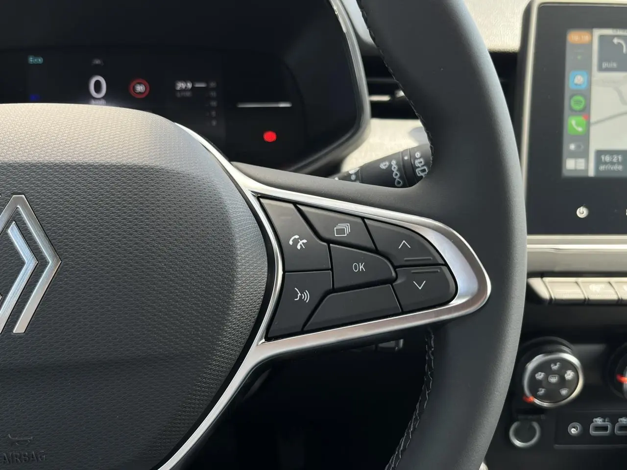 Gros plan sur le volant multifonction noir de la Renault Clio 2025 avec commandes intégrées et tableau de bord numérique en arrière-plan.