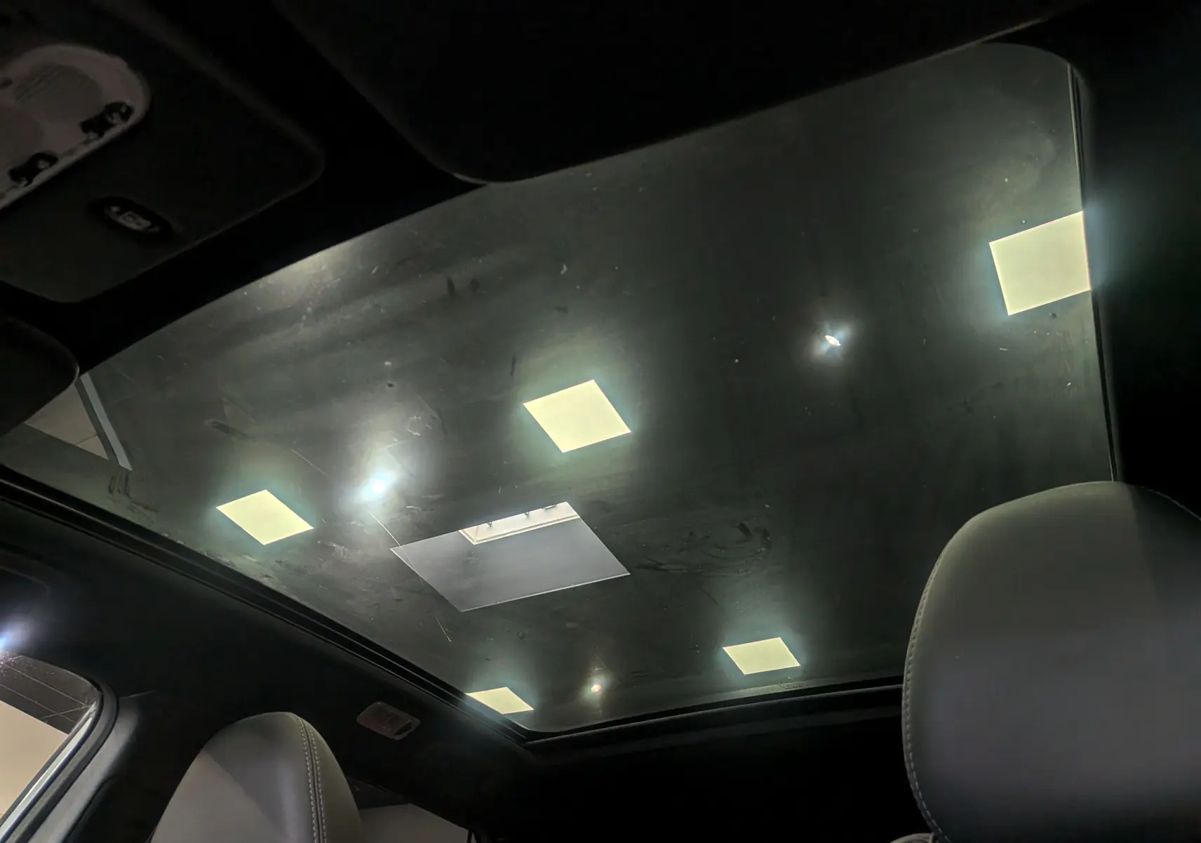 Toit panoramique en verre vu de l'intérieur du Nissan Qashqai gris perle, avec sièges en cuir noir visibles.