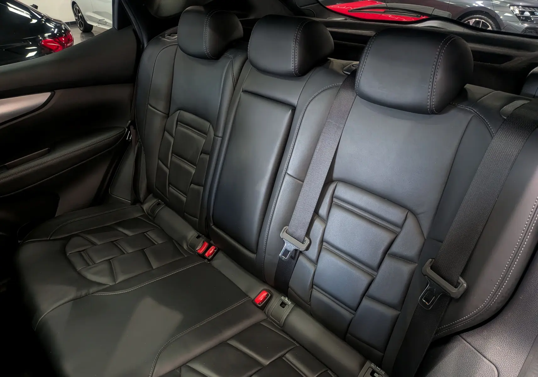 Vue intérieure des sièges arrière en cuir noir du Nissan Qashqai 2018, soulignant les ceintures de sécurité et les appuie-têtes.